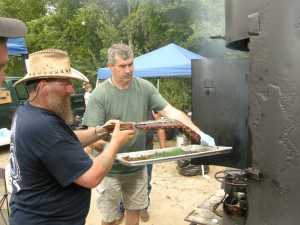Kelly Magni and Ted Turgeon of the Southwick TAC team return a rack of pork ribs to the smoker after basting last year at the annual Grill'n Daze barbeque competition sponsored by the Southwick Rotary Club. The TAC team took second for their beef entry. (File photo ©2012 Carl E. Hartdegen)