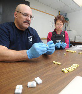 Det. Lt. David Ragazinni and Det. Roxann Bradley count some of the heroin packets seized by city detectives in two unrelated raids Friday. (Photo by Carl E. Hartdegen)
