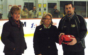 St. Mary's coach Mike Goodreau accepts a defibrillator donated by the Kevin Major Youth Sports Foundation in 2012 during the break between the second and third periods. Susan Canning, mother of the late Kevin Major, center, stands alongside Shannon Small, far left. (File photo by Chris Putz)