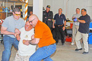 Southwick Reserve Police Officer Jesse Rizzo, front center, is helped to the ground after being shot in the back with a Tazer by Belchertown Police Officer Edward Dey, right, during a Tazer training session at the Southwick Police Department Saturday. Dey is also the Belchertown police department's chief firearms instructor. (Photo by Frederick Gore)