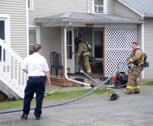 Deputy Fire Chief Mark Devine supervises as firefighters bring a hose into a Franklin Street house which was damaged by a fire yesterday afternoon. (Photo by Carl E. Hartdegen)