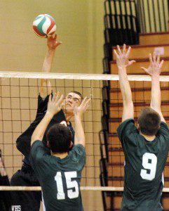 Westfield's Drew Majka, rear, spikes the ball as Minnechaug's Christopher Spock, foreground left, and Mitchell Keegan, foreground right, set for the double block during last night's game in Westfield. (Photo by Frederick Gore)