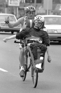 Ricky Hoyt rides in his custom bicycle seat as his father, Rick, pedals on East Main Street in 1992. (Photo ©1992 Carl E. Hartdegen)