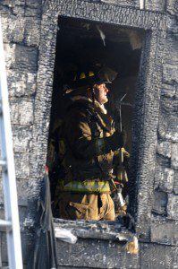 Firefighter Chris Kane is seen through the charred frame of a wndow as he works to ensure that a fire last night at an Aldrich Drive home is fully extinguished. (Photo 2013 Carl E. Hartdegen)