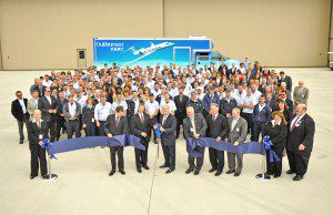 Fran Ahern, front center left, general manager of Gulfstream Westfield, and Larry Flynn, front center right, hold a ceremonial pair of scissors after a ribbon cutting ceremony of the new $26 million Gulfstream project at Barnes Regional Airport.  (File photo by Frederick Gore)