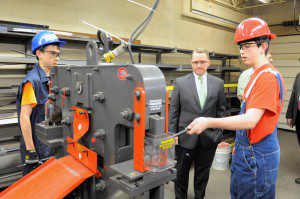 Gateway Regional High School freshmen students, John Rooney, left, and Brendan MacKechnie, right, explain how to safely bend a piece of steel in a 55-ton press to Lt. Gov. Timothy P. Murray, background, during a tour of the school's welding class yesterday. Murray plans to visit 64 vocational schools to promote workforce training, technology, engineering and math. (Photo by Frederick Gore)