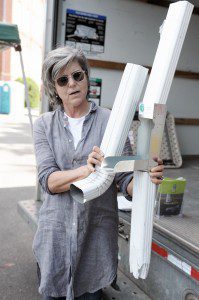Suzanne A. Gebelein, of The Great American Rain Barrel Company, of Hyde Park, demonstrates how to use the "diverter" option which attaches to a downspout to improve the water collecting process. (Photo by Frederick Gore)
