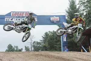 Professional motocross racer John Dowd, right, of Chicopee, watches his son Ryan, left, 16, during a practice run at the Southwick MX338 track yesterday. Racers from around the world are arriving in Southwick for tomorrow's Lucas Oil Pro MotoCross National. (Photo by Frederick Gore)