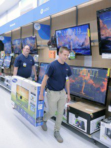 Chris Weiss, left, and Tyler Hardie, right, sales associates at the Westfield Walmart, carry a large screen television to a display area of Walmart in preparation of the upcoming tax-free weekend August 10 and 11. (Photo by Frederick Gore)