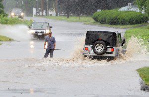 A man attempts to warn drivers how deep the water is on Mainline Drive in Westfield yesterday after a fast moving storm hit the area. Many SUV drivers ignored the knee-deep water and went around the man. (Photo by Frederick Gore)