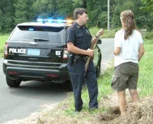 Officer Steven Carrington discusses a twisted and rusted rifle with the Westfield woman who found the remains of the gun near the edge of Fowler Road Monday morning. (Photo by Carl E. Hartdegen)