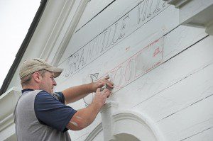 Nate Padden, of Monson, a professional stencil artist, outlines the front entrance way of the Granville Village School yesterday as preparations are in place for the upcoming school year. The school is receiving much needed improvements. (Photo by Frederick Gore)
