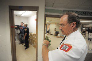 Southwick Fire Chief Richard Anderson, foreground, checks his watch after a fire inspector activates a pull box alarm at Woodland Elementary School. Contractors have installed a talking alarm system that will verbally inform everyone of the emergency. Checking the system in the master control room. left, is Southwick Fire Inspector Ralph Vecchio and Mark Parent, foreman of Schmidt Electric. (File photo by Frederick Gore)