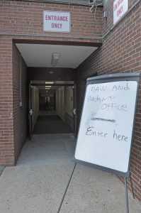 A portable white board located on the east side of the school now indicates the temporary entrance for students and visitors. (Photo by Frederick Gore)