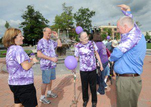 Participants in a walk at Park Square to raise money for the Alzheimer’s Association look on as Westfield Mayor Daniel Knapik dons a purple tee shirt he bought at the fundraiser Thursday. (Photo by Carl E. Hartdegen)