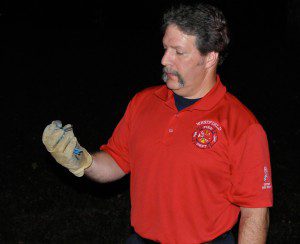 Firefighter Roger Bernier holds a fledgling bluebird rescued from utility wires in his gloved hand. (Photo by David Bogdan)