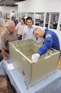 Randy Bresnik, right, an astronaut on the STS-129 Atlantis, uses a pair of white cloth gloves to check a specially designed aluminium shipping container that will be used to transport spacesuits to and from the International Space Station as Advance Manufacturing Plant Manager, left, Tom Scott-Smith and Jeffrey Amanti, center, production manager, monitor the informal inspection. Bresnik and a handful of Johnson Space Center employees visited the plant Friday where the $50,000 container was constructed. (Photo by Frederick Gore)