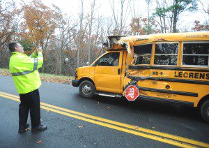 Officer Joseph Maxton makes a picture of a school bus which was struck by the trailerr of a tractor trailer rig yesterday afternoon on Springdale Road. (Photo by Carl E. Hardegen)
