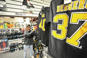 Alex Cerri, manager of DK's Hockey and Lacrosse Pro Shop at the Amelia Park Ice Arena in Westfield, center, arranges a new shipment of jerseys and hockey apparel. The pro shop is located in the former concession stand. (Photo by Frederick Gore)