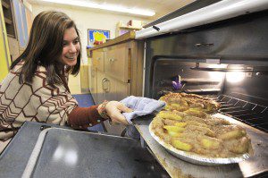 Southwick-Tolland-Granville Regional High School senior Sadie Burnham checks a pair of freshly made apple crumb pies as part of a donation to the Our Community Food Pantry in Southwick. Students from the Food and Nutrition class made more than 85 pies that were delivered to the pantry for distribution Tuesday. (Photo by Frederick Gore)