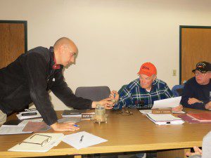 DPW Director Randy Brown, left, shows a broken water meter to water commissioners Luther Hosmer and Edward Johnson. The private meter is believed to have been broken by a tree cutting service. (Photo by Hope E. Tremblay)