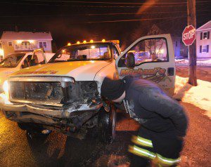 An employee of Michael's Towing speaks with Officer Michael Csekovsky at the scene of a four vehicle  automotive crash on Russell Road, Thursday evening which involved one of the company's tow trucks. (Photo by Carl E. Hartdegen