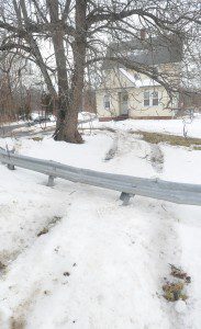 Tracks in the snow on the southeast corner of the intersection of Root and North roads indicate where a pickup truck sailed over the guard rail and came to rest against the front steps of the house early Saturday morning. (Photo © 2013 Carl E. Hartdegen)