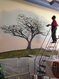Local artist Jeri Hamel on the ladder at the Chester Elementary School library. (Photo submitted)