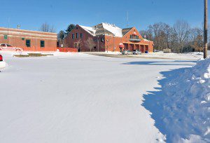 A flat snow-covered section of pavement, foreground, where the former Southwick Department of Public Works was razed last week. The building was was removed by a New Hampshire company. (Photo by Frederick Gore)