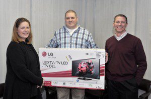 Sue Fox, left, of Southwick, accepts a new 32-inch LED television from Westfield News Sports Editor Chris Putz, center, after winning the Beat the Putz football contest sponsored by the Westfield News. Joining in the presentation is Westfield News President Patrick Berry. (Photo by Frederick Gore)