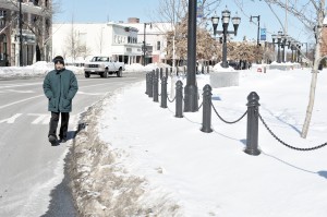 Sidewalks around the Park Square Green remain unusable as a resident walks in an Elm Street traffic lane Monday.(Photo by Frederick Gore)