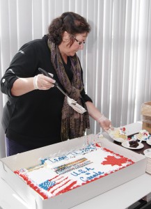 Amelia Park Board of Director member Sue Figy, cuts a special homemade team USA vs. Canada Olympic cake as fans gathered at the rink to watch Westfield's Kacey Bellamy. (Photo by Frederick Gore)