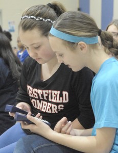 Munger Hill Elementary School fifth-grade students Maggie Prystowski, left, and Chandler Pedolzky use a handheld device to communicate during a question and answer session as part of a Westfield Gas & Electric safety program Friday. (Photo by Frederick Gore)