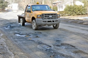 The rear wheel of a city-owned vehicle slams into a pothole on Shaker Road in Westfield yesterday. (Photo by Frederick Gore)