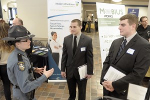 Jillian M. Monahan, a Maine State Police trooper, explains some of the duties and responsibility of a Maine state trooper to Westfield State University students Adam Healey, center, and Bryan Ring, right, during a career fair at the university yesterday. (Photo by Frederick Gore)