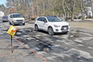 A bright orange piece of rope protects the front lawn of a Shaker Road resident after drivers were using the lawn to avoid the potholes. (Photo by Frederick Gore)