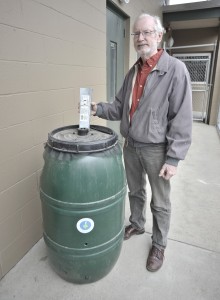 Water Resource Engineer Charles Darling holds an optional down spout adapter while standing with a new 60-gallon rain barrel. Residents can order the $69 barrel by calling 1-800-251-2352 by 5 p.m. June 5, 2014 with pick up in the City Hall parking lot June 12, 2014 from 4 - 6 p.m. (Photo by Frederick Gore)