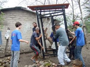 Nick Fanion waits at a prepared pit as village residents and church volunteers (including his brother, Zachary Fanion, right) move the frame of a pit toilet to the hole during a mission to the El Pilon, a remote village in Honduras. Members of Wyben Church are raising funds to make another trip to improve sanitation in the village. (Photo courtesy Holly Fanion)