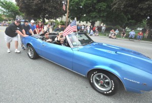 Harvey Buckland and other veterans ride in a convertible Pontiac Firebird driven by Ron Gibbons of Westfield but powered by a group of Cub Scout parents after the car’s engine overheated yesterday during the Westfield Memorial Day parade. (Photo © 2014 Carl E. Hartdegen)