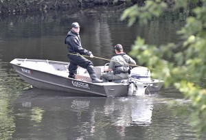 A Massachusetts Environmental Police Officer slowly drives a boat in a designated area of the Westfield River as a Massachusetts State Police officer holds a yellow tow-rope that is connected to a Massachusetts State Police Underwater Recovery Team member during a search for a lost swimmer. The swimmer's body was found moments after this photo was taken Sunday morning only about 100-yards from where the swimmer was reportedly having problem swimming Saturday evening. (Photo by Frederick Gore)