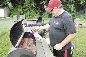 Luke Beauchemin, a member of the Cow Pucks BBQ team of Westfield, sprays a fine mist of water on a rack of slow-smoking meat as part of Grill'n Daze in Southwick, Sunday. The annual event is sponsored by the Southwick Rotary Club. (Photo by Frederick Gore)