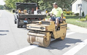 An employee from the Southwick Highway Department uses a roller to flatten out a new adhesive strip of reflective material that is presently being used to mark crosswalks. (Photo by Frederick Gore)