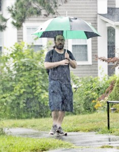 A man carrying a large umbrella attempts to stay dry while walking along Court Street in Westfield yesterday. The heavy rain caused localized flooding across the area. (Photo by Frederick Gore)
