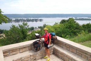 Keith Harris, a Rotarian pedaling across the United States to raise funds for the Rotary Foundation, pauses on the banks of the Mississippi River. (Photo courtesy Rotary District Governor Michael Roy)