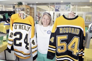 Susan Canning holds a pair of autographed Boston Bruins jerseys signed by Terry O'Reilly and Adam McQuaid as part of the 2014 fundraiser at the Amelia Park Ice Arena in memory of her son Kevin J. Major who was an avid hockey player. Fundraising efforts will continue Wednesday through Sunday with games, raffles, auctions, and more as the fifth year of the memorial tournament comes to Amelia Park Ice Arena again.  (Photo by Frederick Gore)