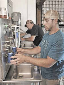 Sergio Bonavita, foreground, a brewmaster at the Westfield River Brewery in Southwick, fills each can of his homemade beer by hand as Rick Berry, a volunteer worker, background, seals the containers at their new location on College Highway in Southwick. Bonavita said he hopes to be open to the public sometime in October. (Photo by Frederick Gore)