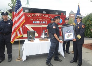 Westfield firefighter Mark Oleksak presents a framed U.S. flag which was flown over Kabul, Afghanistan during Operation Enduring Freedom to Fire Chief Mary Regan during a ceremony Thursday to honor the firefighters who fell along with the World Trade Center in the Sept. 11 terrorist attack on thenation. (Photo by Carl E. Hartdegen)_