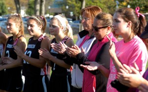 Westfield High School field hockey head coach Karen Gomez, second from right, and assistant Linda Rowbotham, third from right, stand alongside Bombers players, left, and a member of the Longmeadow Lancers, far right, in a show of support to fight back against cancer at Thursday's "memorial" game. (Photo by Chris Putz)