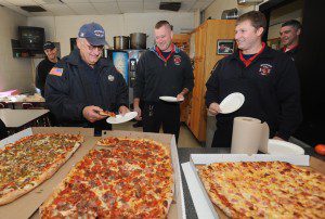 Firefighter Jim Kotowski takes the first slice of pizza Friday as his partner, Scott Bullock, and step-son, Shaun Trant, wait their turn at a party on the last day of Kotowski’s 37-year career at the Westfield Fire Department. (Photo by Carl E. Hartdegen)