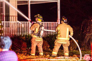 Westfield firefighters Lee Kozikowski and Steven Makos  hose down a burning house at 75 Wildflower Circle Saturday night. (Photo by Liam Sheehan)